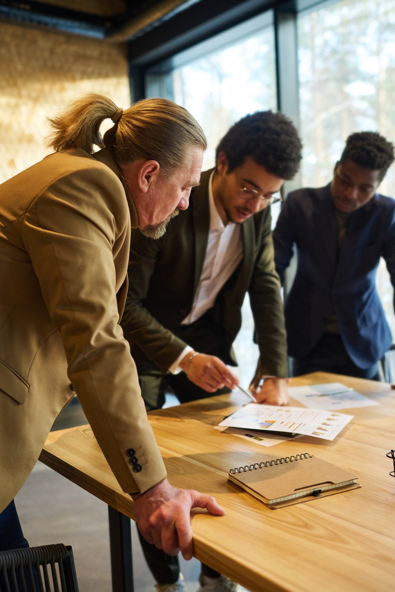 Side view of mature broker listening to explanation of young colleague